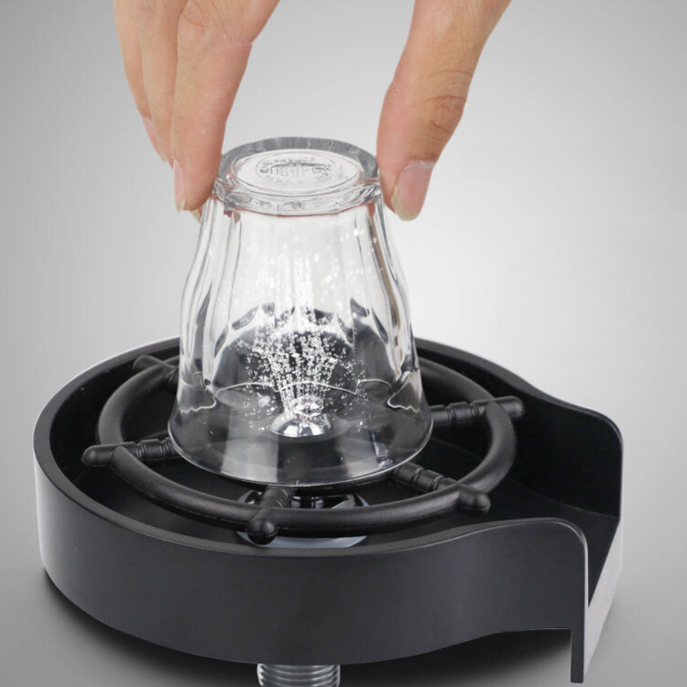  Main appuyant un petit verre retourné sur le rince-verres GlassClean noir pour déclencher les jets d’eau